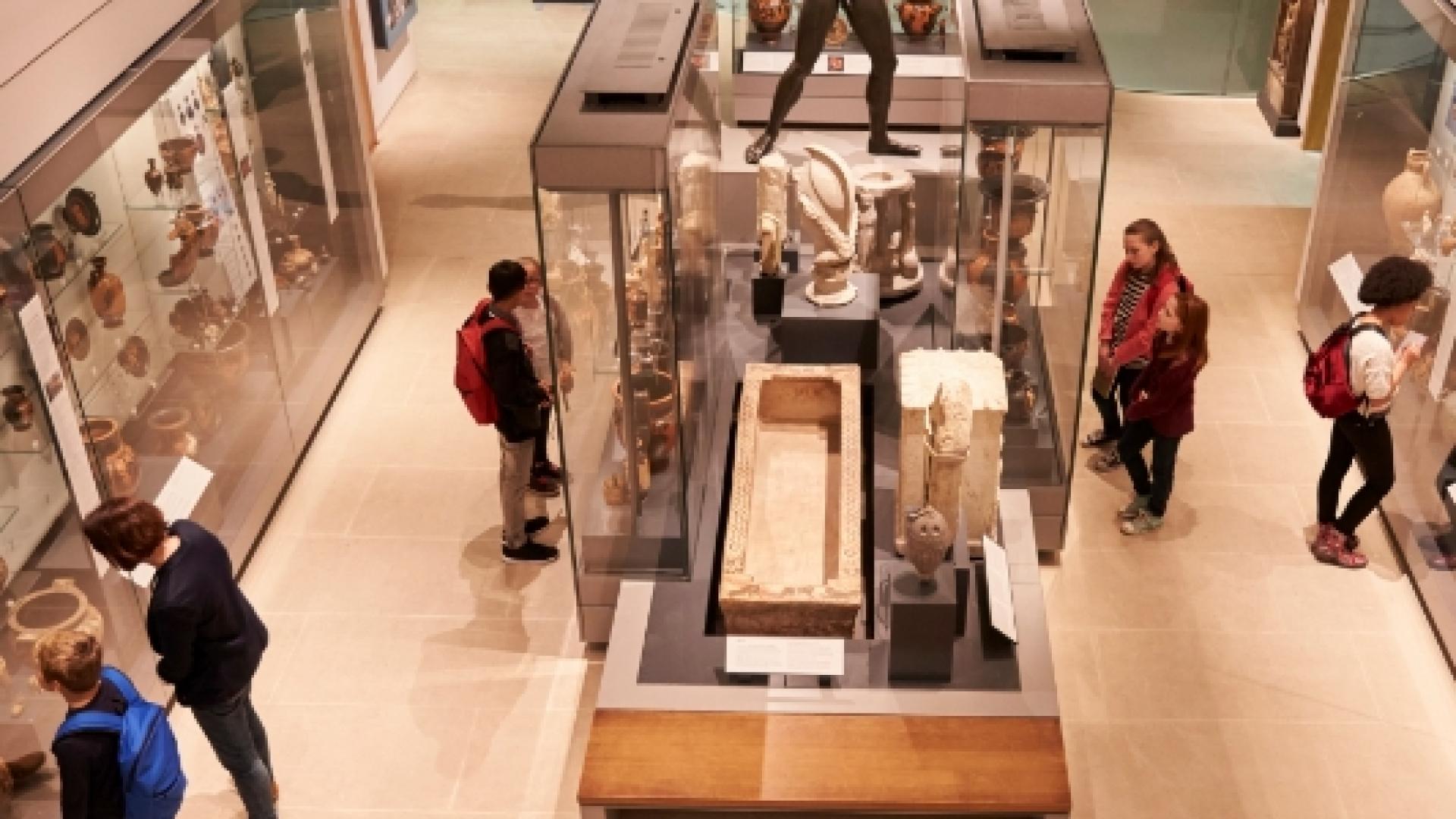 People walking around several glass exhibits in a museum