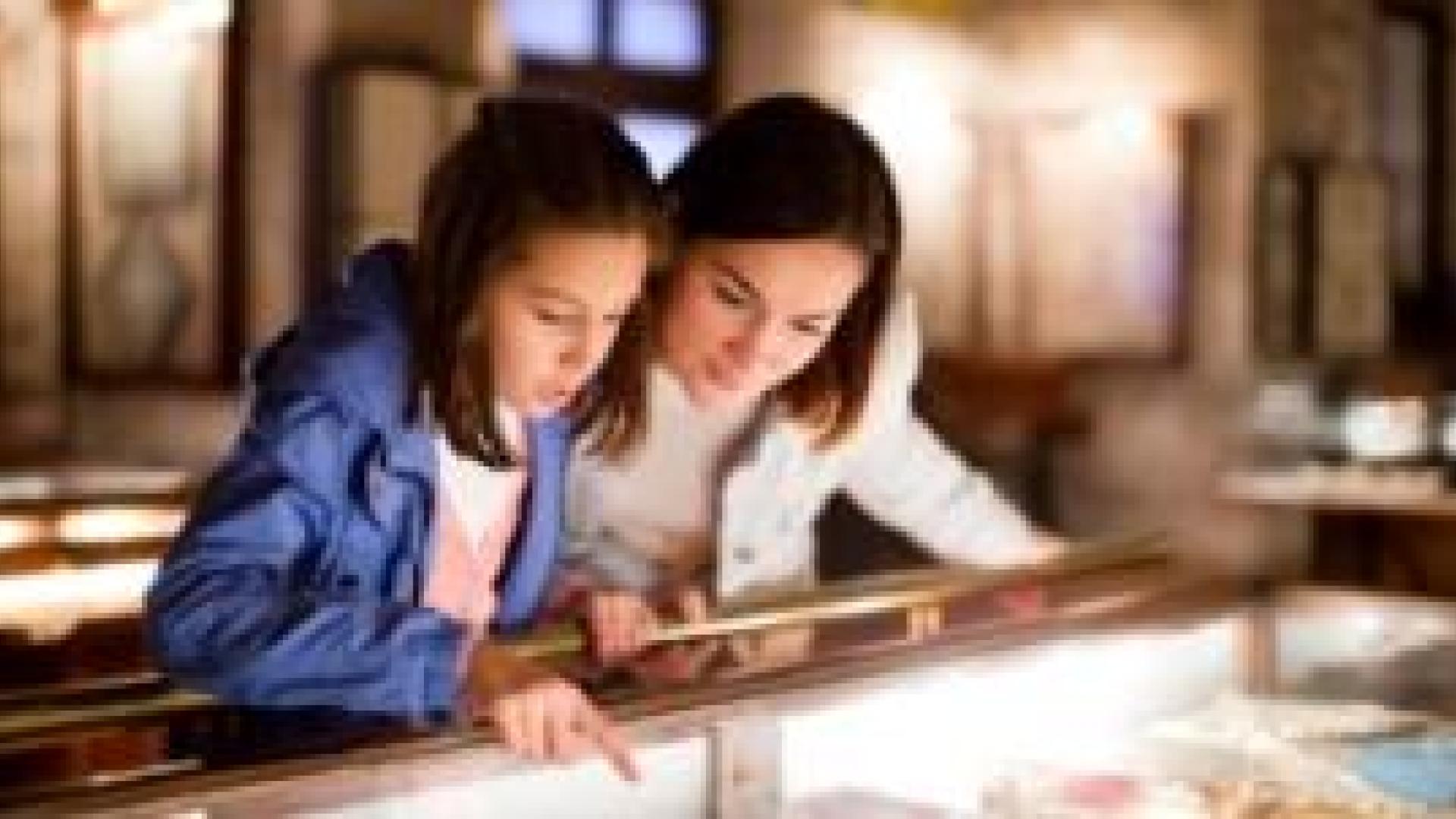 Mother and daughter examining a display in a museum.