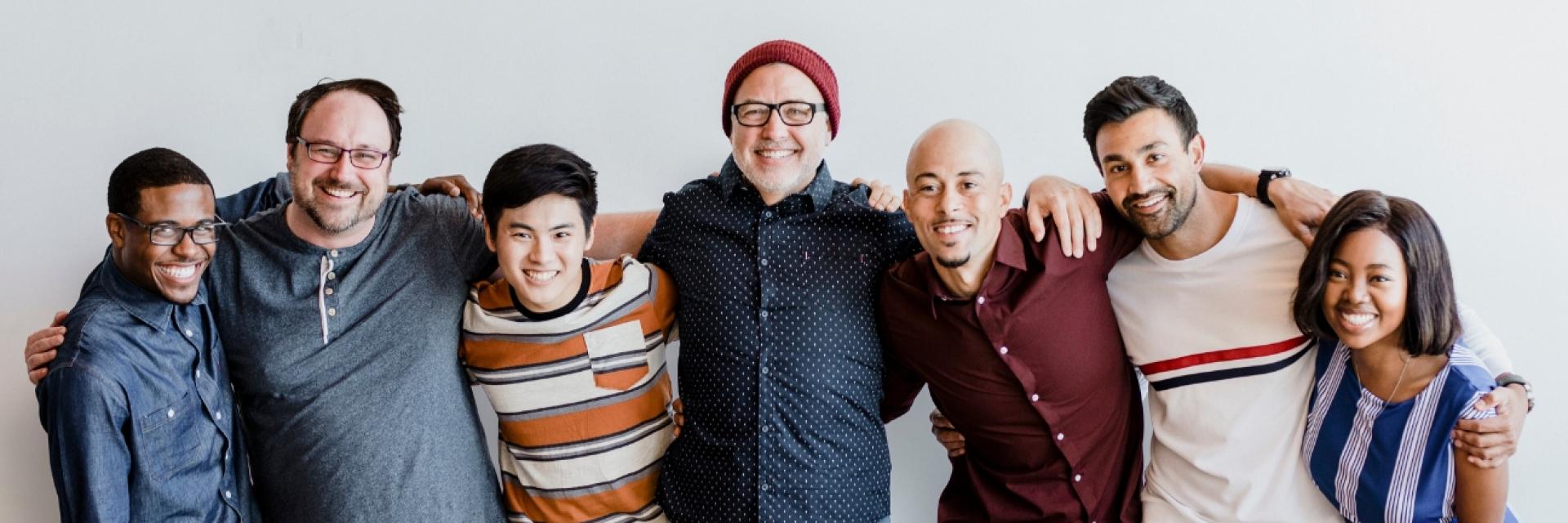 A group of diverse people all in a row with their arms over each other's shoulders