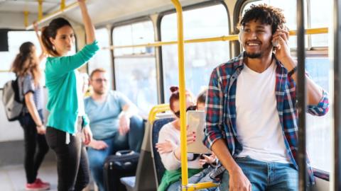 People sitting and standing in public transit bus